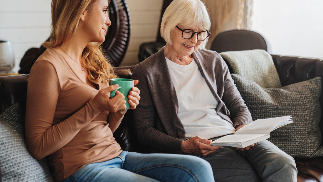 Adult daughter spending time looking at family photos with her mother in aged care