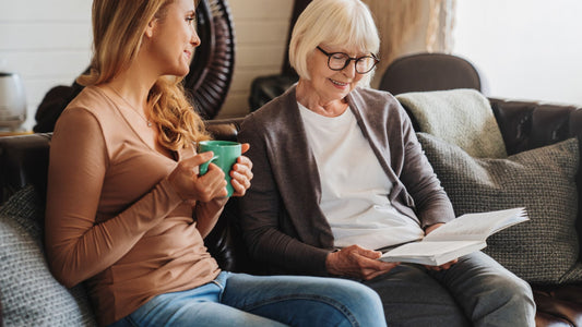 Adult daughter spending time looking at family photos with her mother in aged care